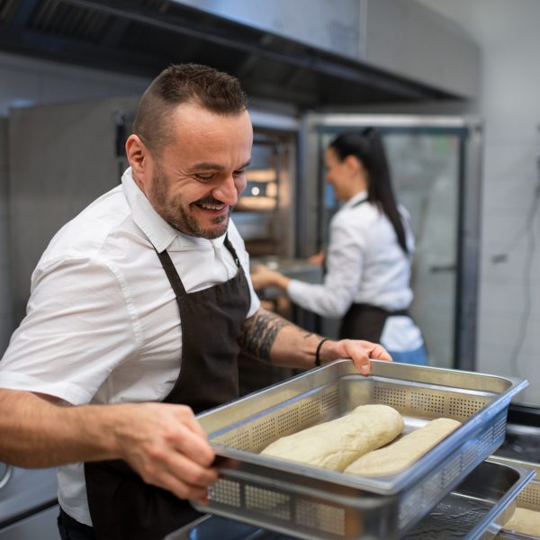 A chef and cook working on their dishes indoors in restaurant kitchen.